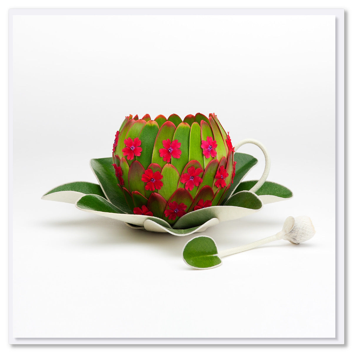 A playful greeting card featuring a cup, saucer and spoon. Created from lush green leaves and dainty red flowers. This quality square card is from Golly Gosh Creations.