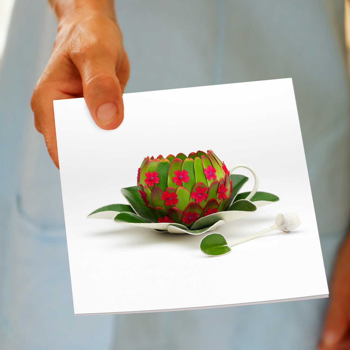 A model holding a quality greeting card, featuring a cup, saucer and spoon. Crafted from leaves and flowers. Size 142 x 142 mm
