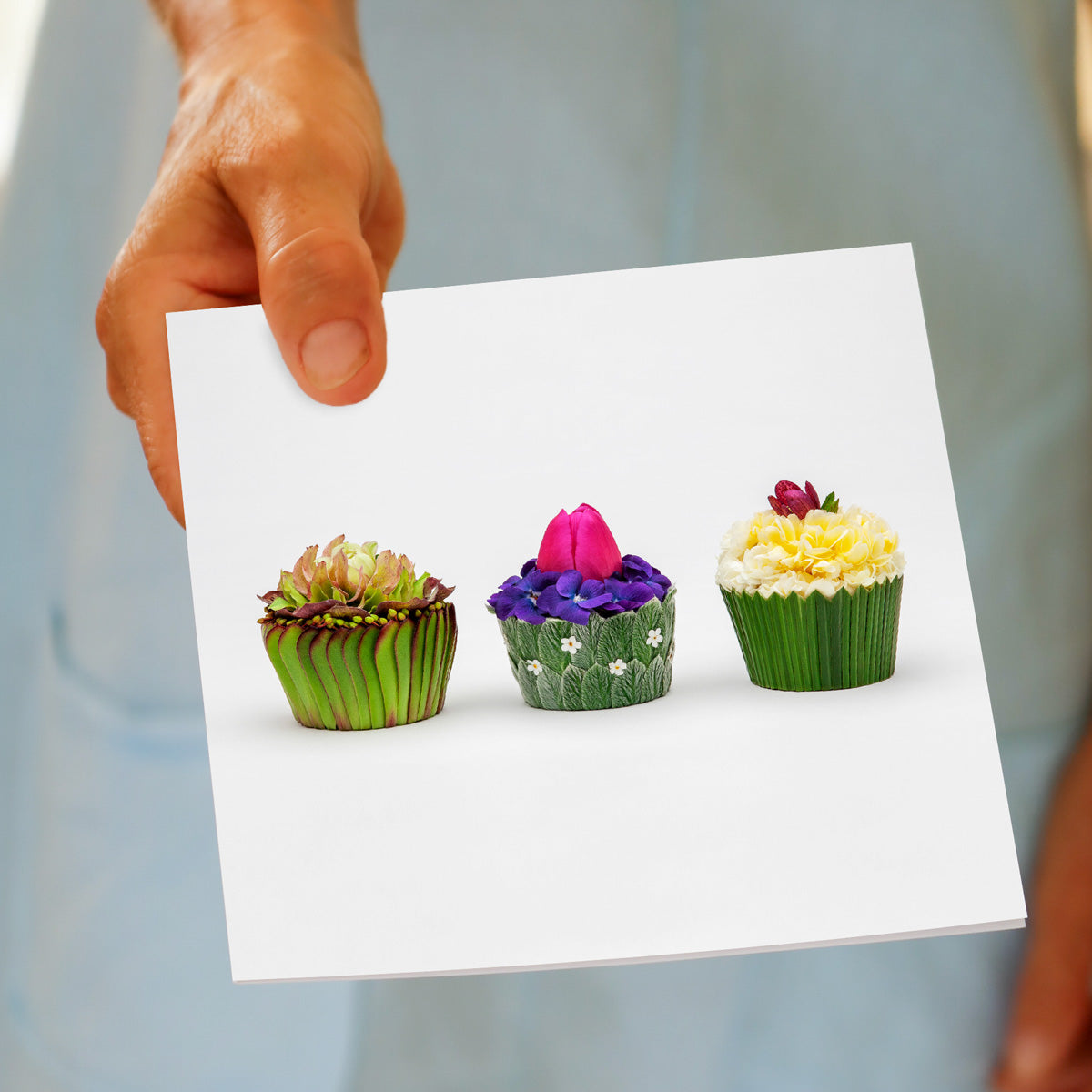 Model holding a floral cupcakes greeting card from Golly Gosh Creations. Delightfully created from dainty flowers and leaves. Size 142 x 142 mm