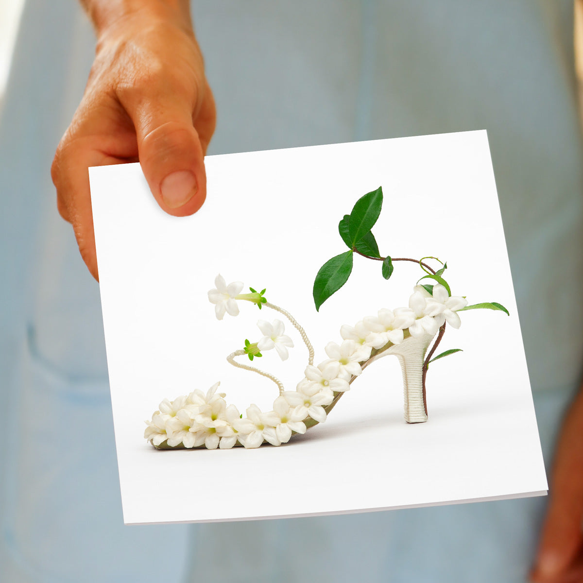 A hand held stephanotis shoe greeting card found at Golly Gosh Creations. Size 142 x 142 mm. Created from white stephanotis blooms on a white background.