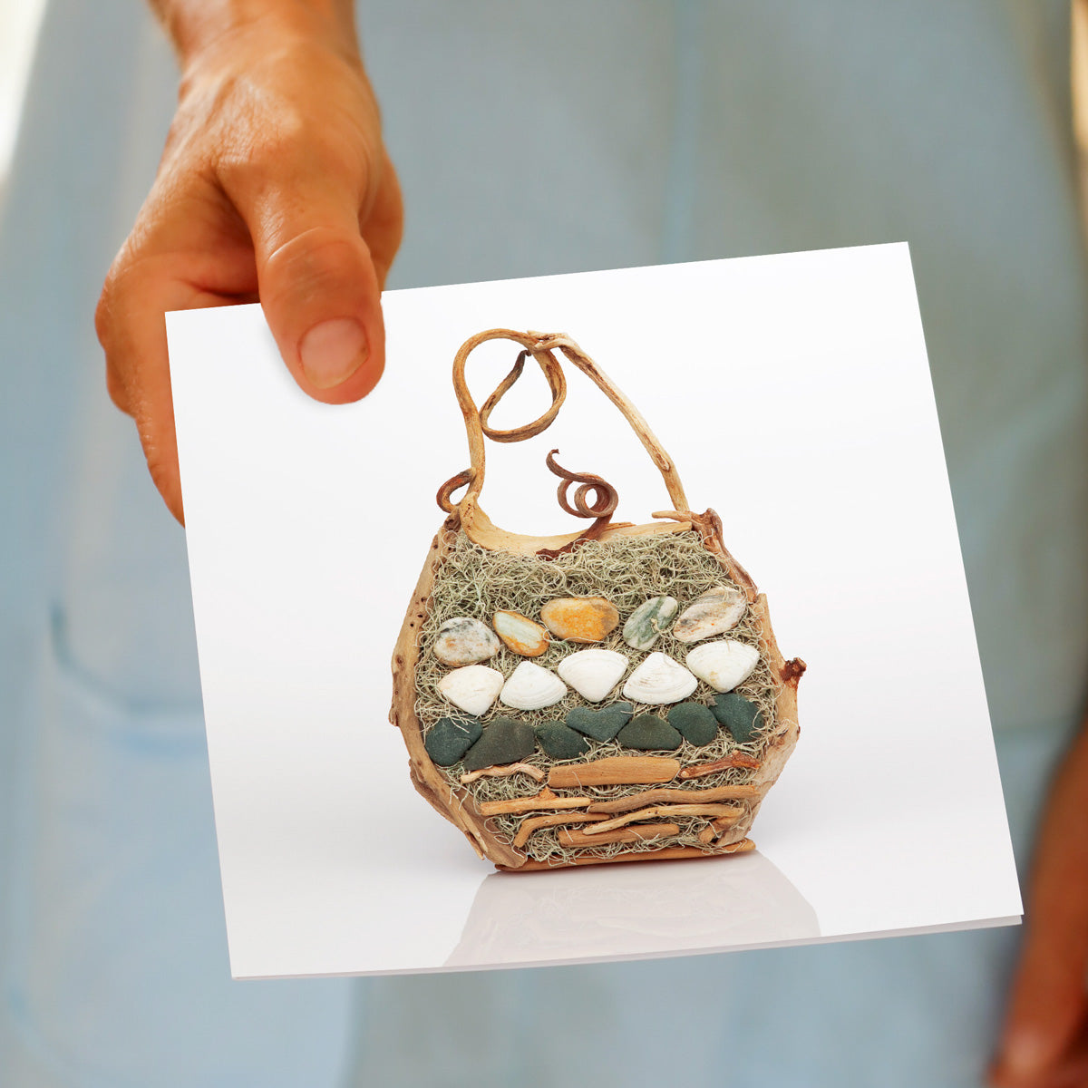 A model holding a beach bag greeting card from Golly Gosh Creations. Created using gathered stones and sticks.