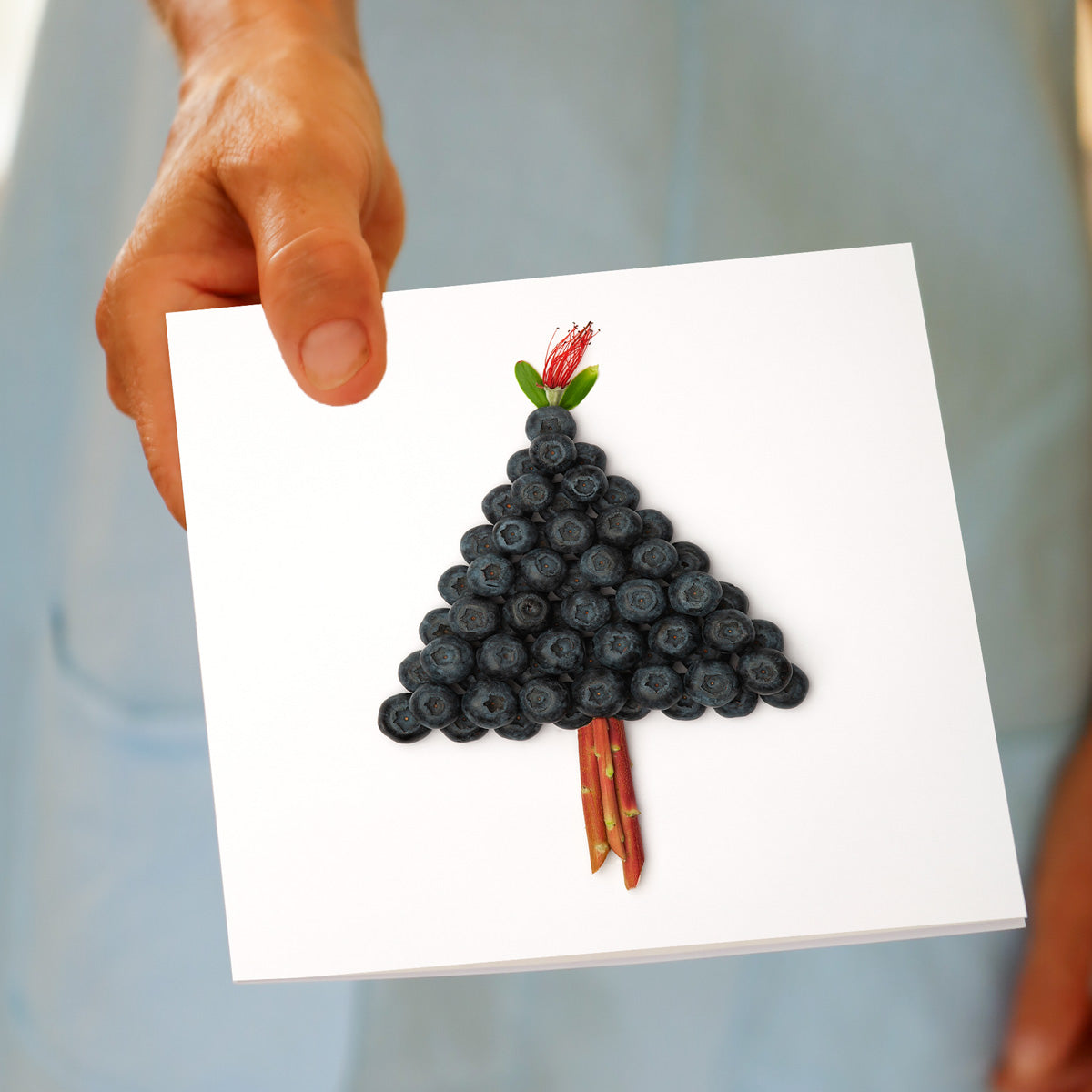 Hand holding the Christmas Blueberry Tree greeting card, showing the blueberry tree design