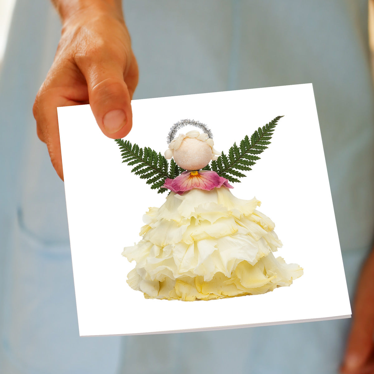 Hand holding the Christmas Cream Angel greeting card, showing the cream flower angel design