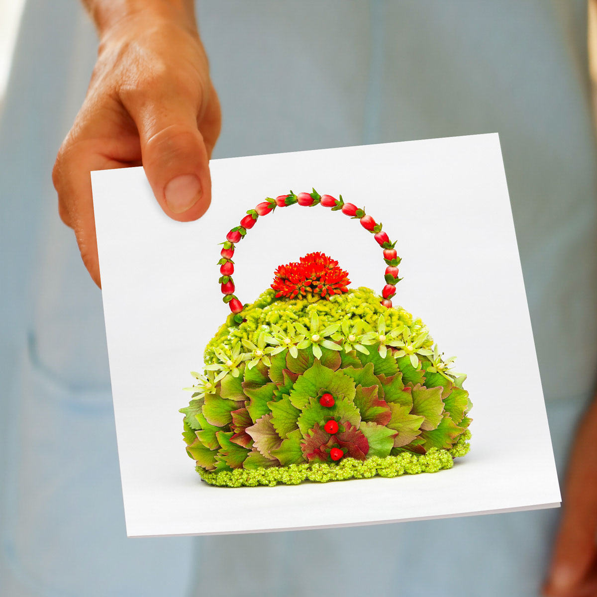 A hydrangea petal bag greeting card being held by hand. Created from lush green hydrangea petals. Available from Golly Gosh Creations. Size 142 x 142 mm.