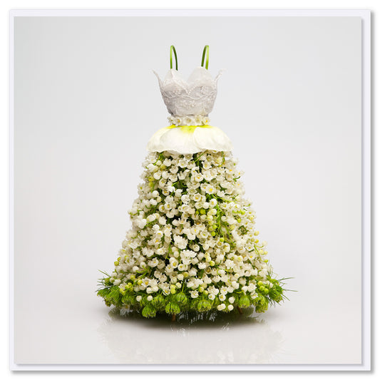 Floral formal dress made of white blossoms with lace bodice, green calla lily straps, and green flowers at base against white background