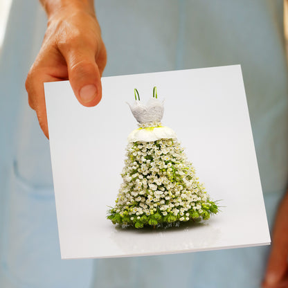 Hand holding Lace Bodice Dress greeting card featuring elegant floral gown made of white flowers with green accents