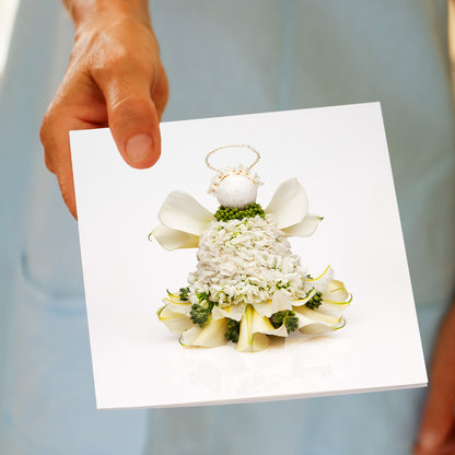 Hand holding the Christmas Lily Angel greeting card, showing the lily flower angel design
