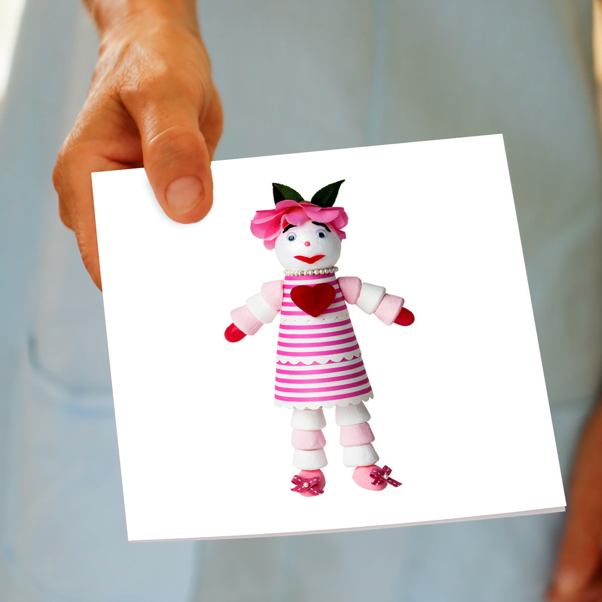 A marshmallow doll greeting card being held by hand from Golly Gosh Creations.
A generous square card created from an assortment of marshmallows.
