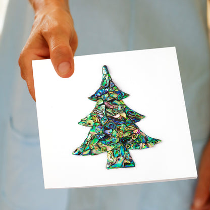 Hand holding the Christmas Paua Tree greeting card, showing the paua shell design