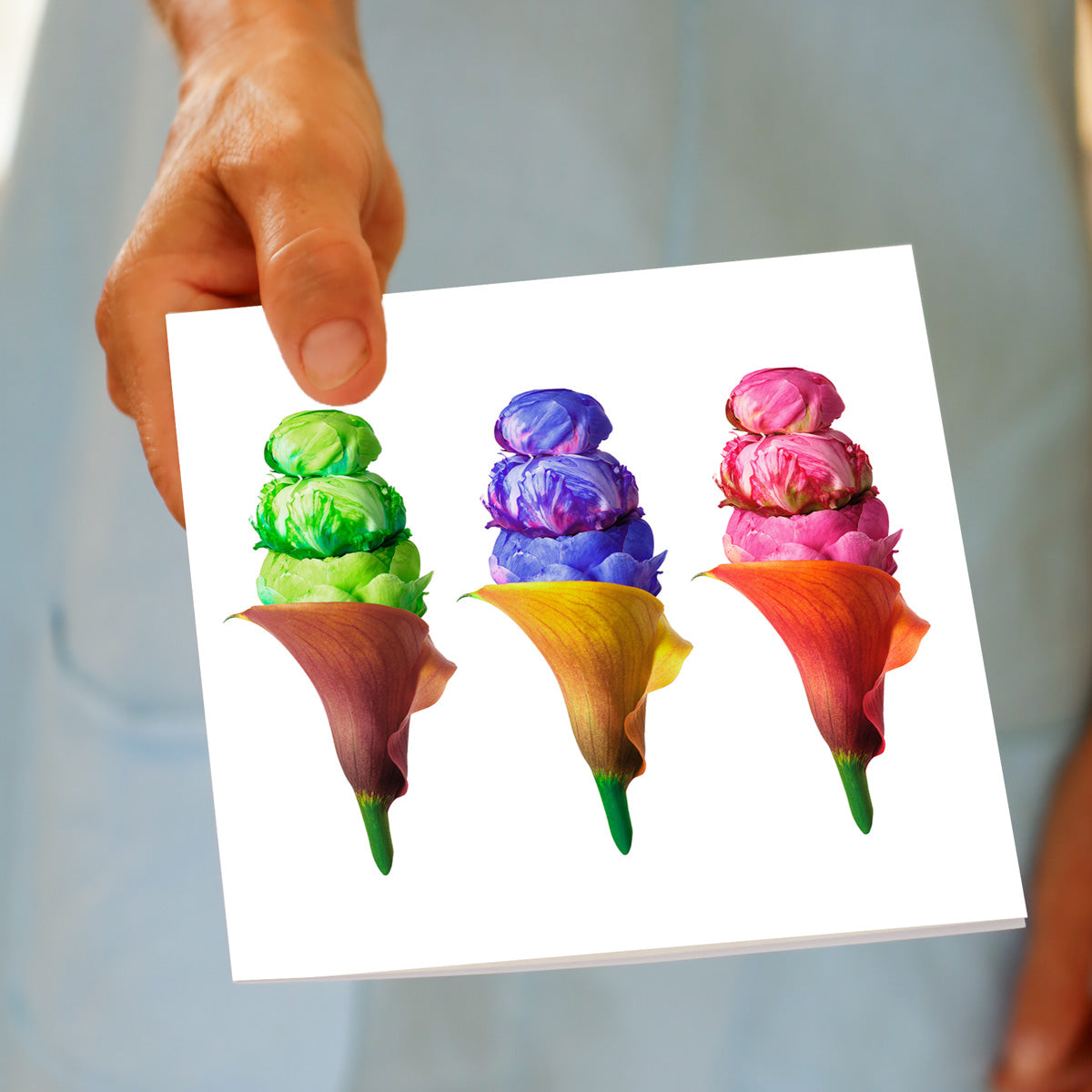 Hand displaying Peony Ice Cream Trio card with three floral ice cream arrangements featuring peony scoops in green, purple, and pink served in calla lily cones