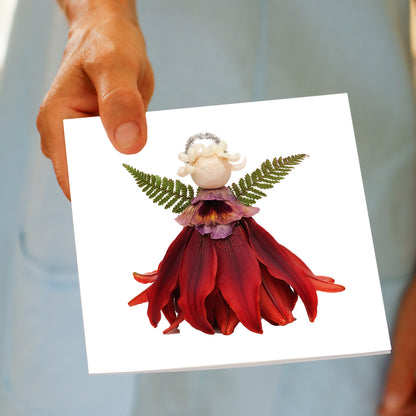Hand holding the Christmas Red Angel greeting card, showing the red flower angel design