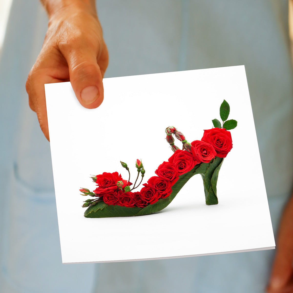 A hand held red rosebud shoe greeting card from Golly Gosh Creations. A generous square card created from alluring fresh red roses, buds and leaves.