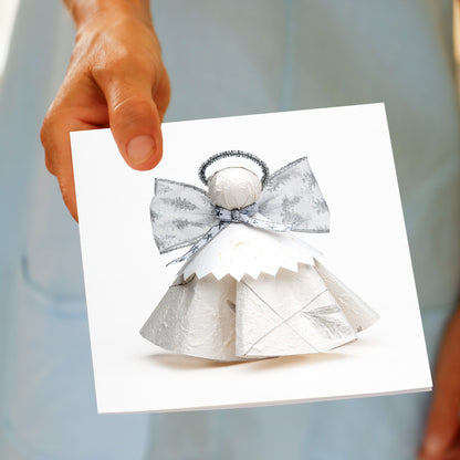 Hand holding the Christmas Silver Angel greeting card, showing the paper angel design