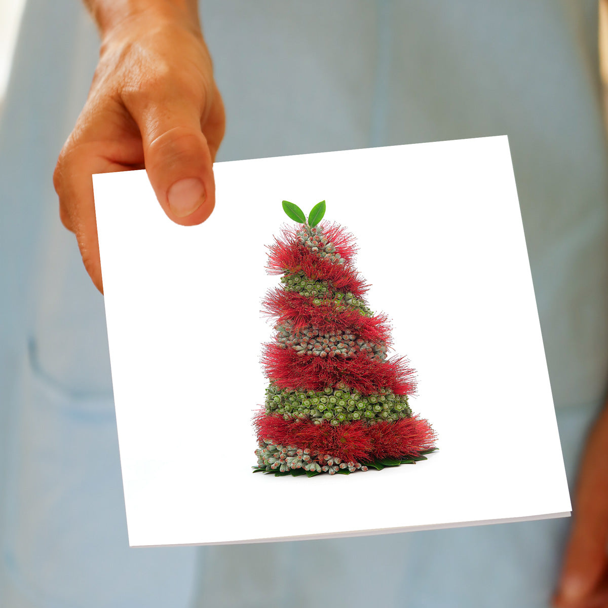Hand holding the Christmas Spiral Pohutukawa Tree greeting card, showing the spiral flower design