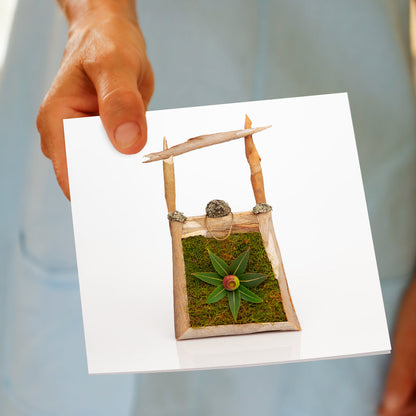 A model hand holding a eucalyptus tree bark and leaf bag greeting card from Golly Gosh Creations. Created from real foliage that sits on a white background.